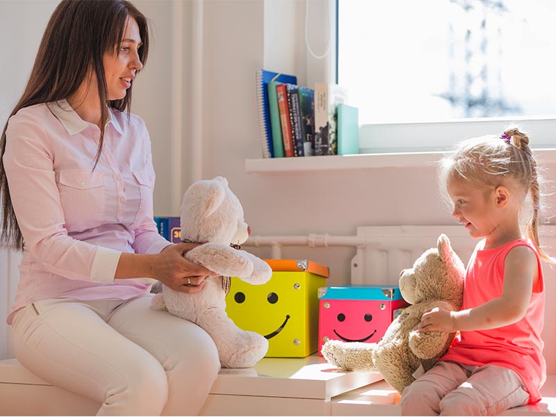 mulher de frente para uma criança com brinquedos